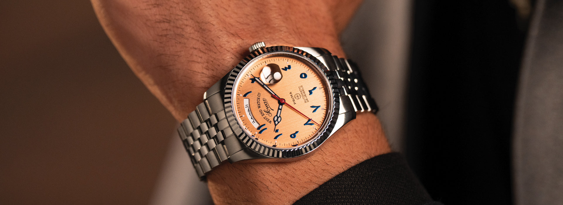 West End automatic watch with Arabic numerals and stainless steel bracelet, worn on wrist
