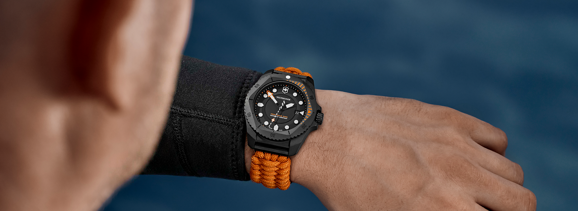 Victorinox Swiss Army watch with black dial and orange braided strap worn on the wrist during an outdoor adventure.